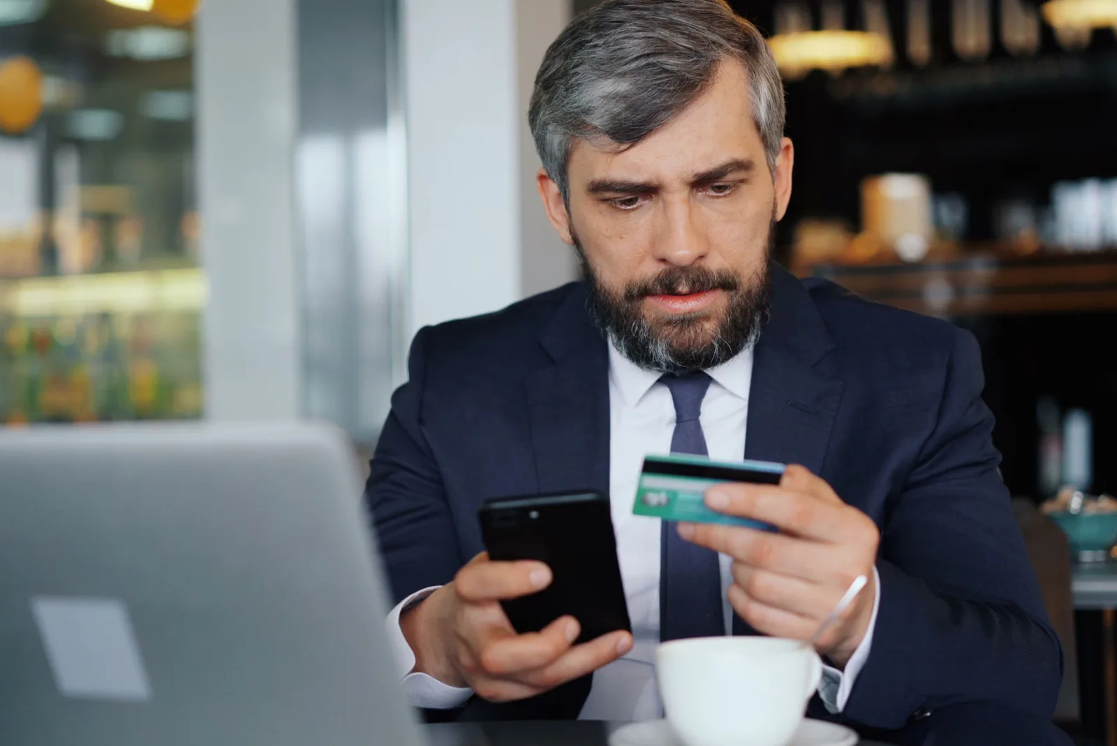 Personne consultant un comparatif de banque en ligne gratuite sur ordinateur, cartes bancaires sur le bureau.