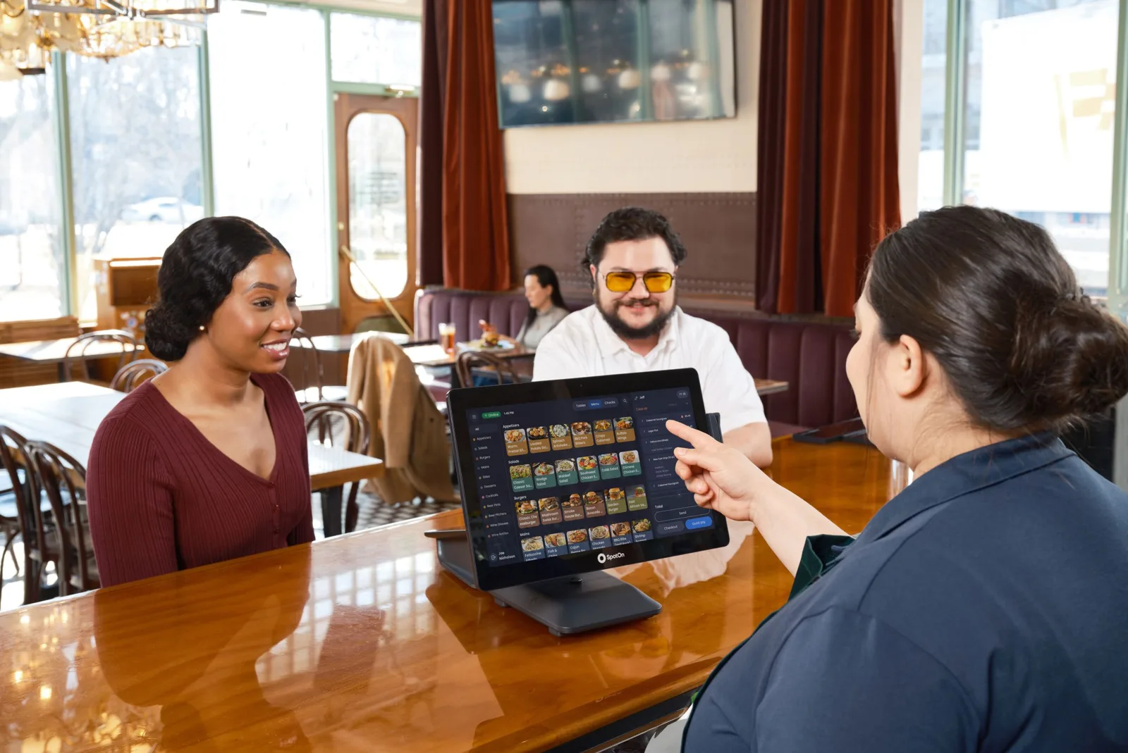 Photo réaliste d'une cantine avec tables et plateaux, une agente consulte les réservations sur tablette.